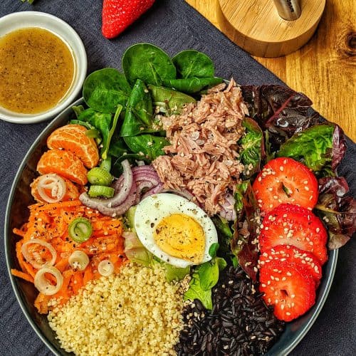 Eine dekorative Bowl mit Reis, Couscous, Salat und Thunfisch.