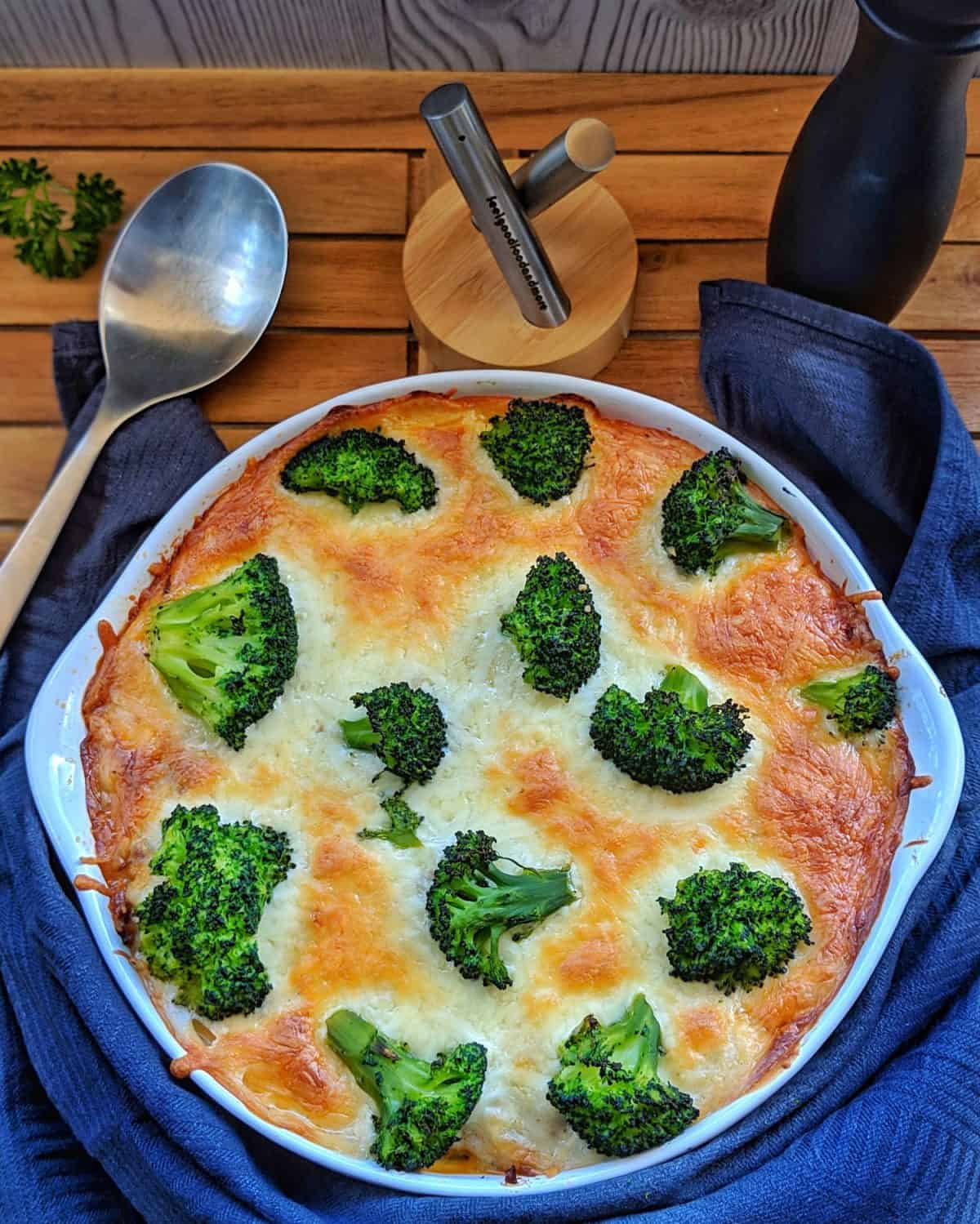 Eine runde weisse Auflaufform mit dem Brokkoli-Nudel-Auflauf mit Hackfleisch.