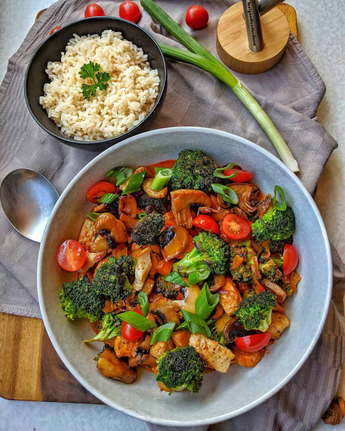 Ein tiefer Teller mit Putengeschnetzeltem mit Champignons und Brokkoli. Dahinter eine Schale Reis