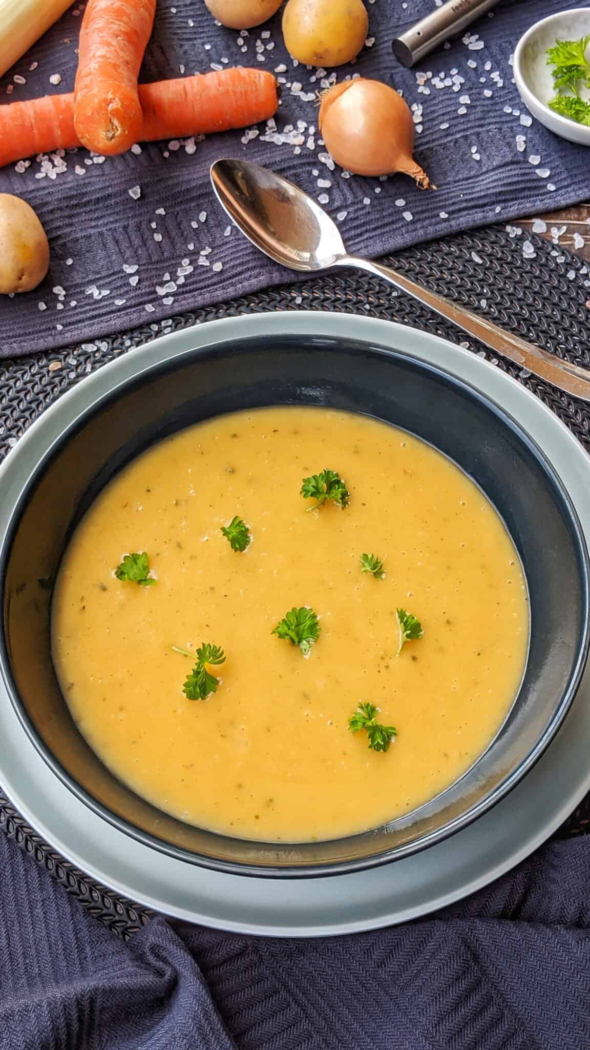 Ein Teller mit Kartoffelsuppe. Darüber Gemüse als Deko.