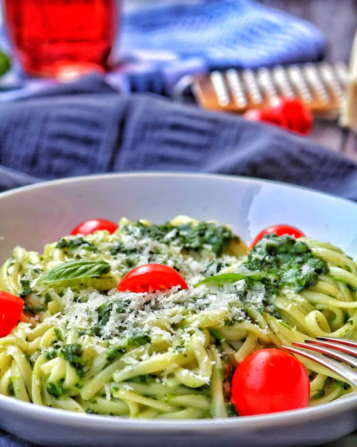 Ein tiefer weisser Teller mit dem Spaghetti Gericht. Im Hintergrund Deko.