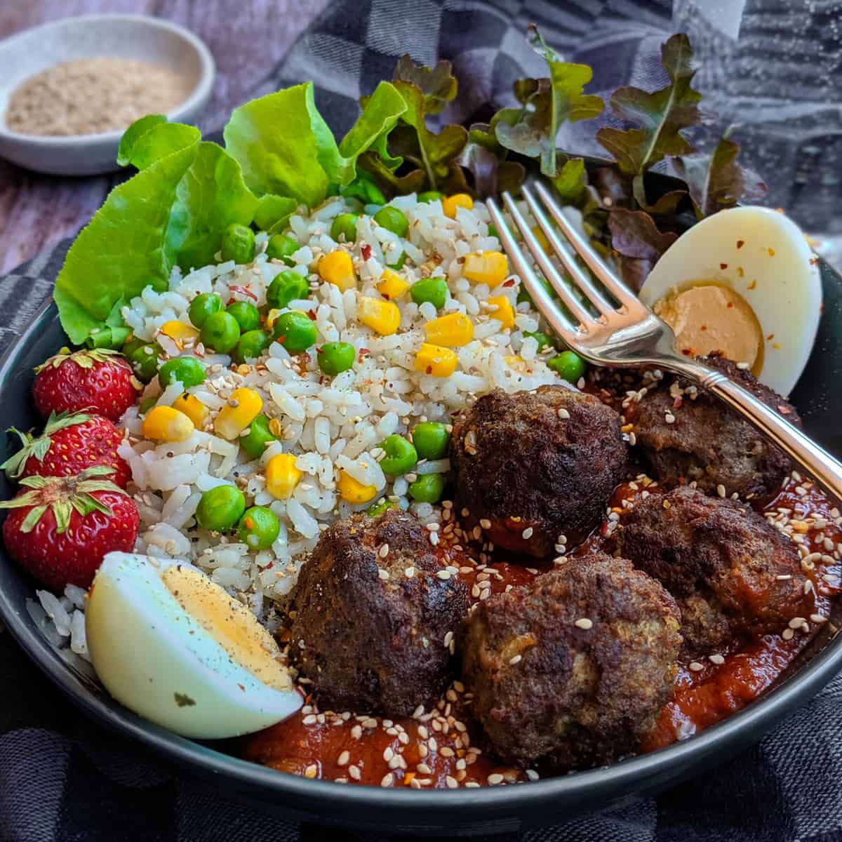 Eine Reis Bowl mit Hackbällchen und Tomatensoße.