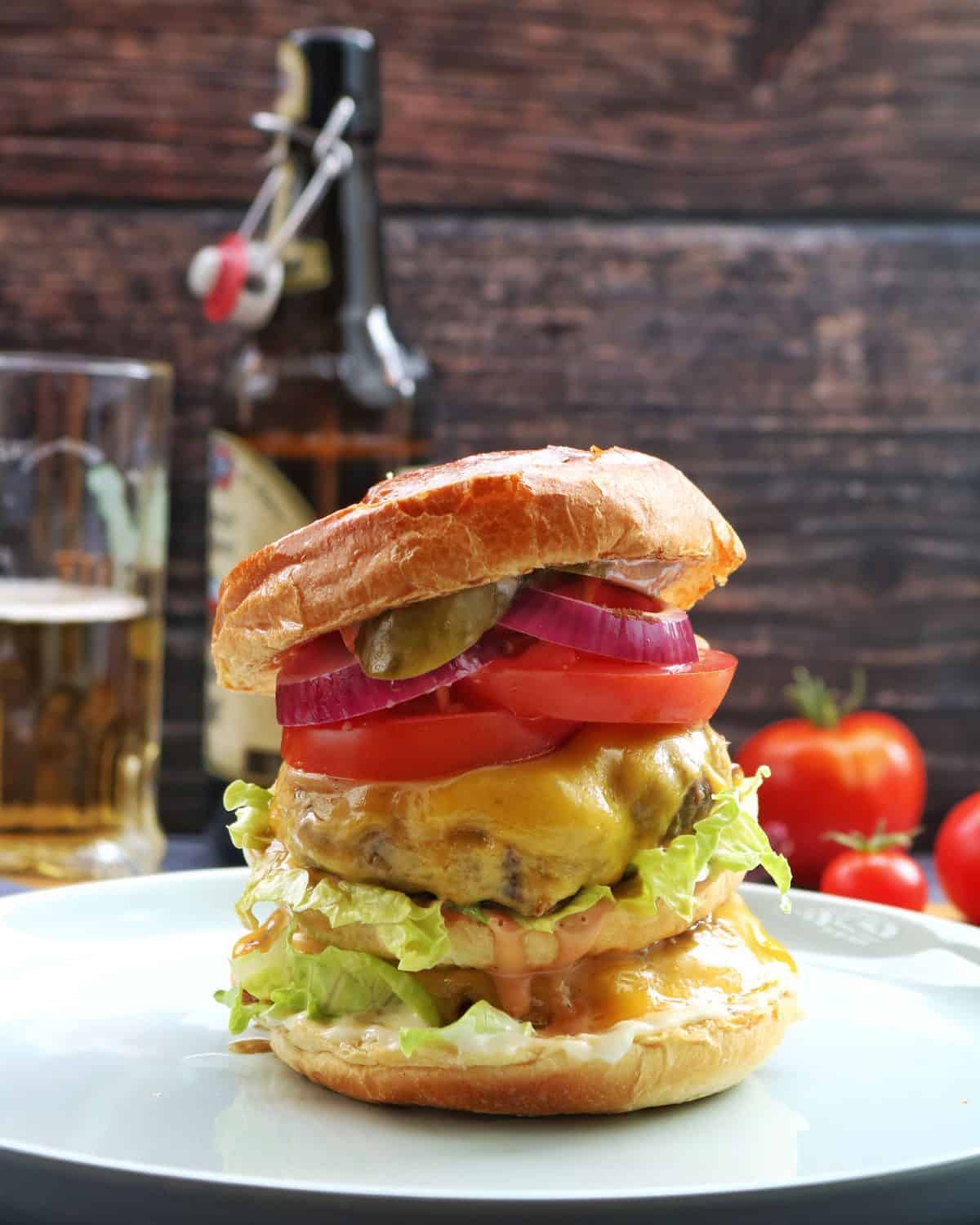 Ein double Cheeseburger auf einem hellen Teller. Im Hintergrund Deko.