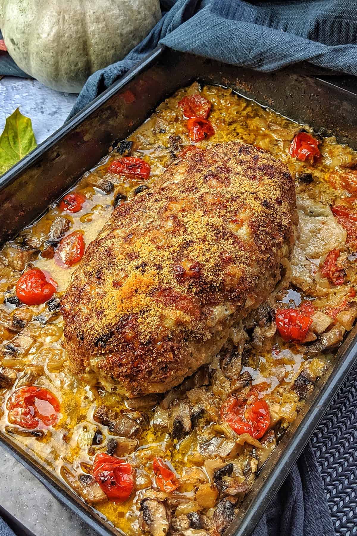 Hackbraten in einer Auflaufform mit Tomaten und Pilzen.