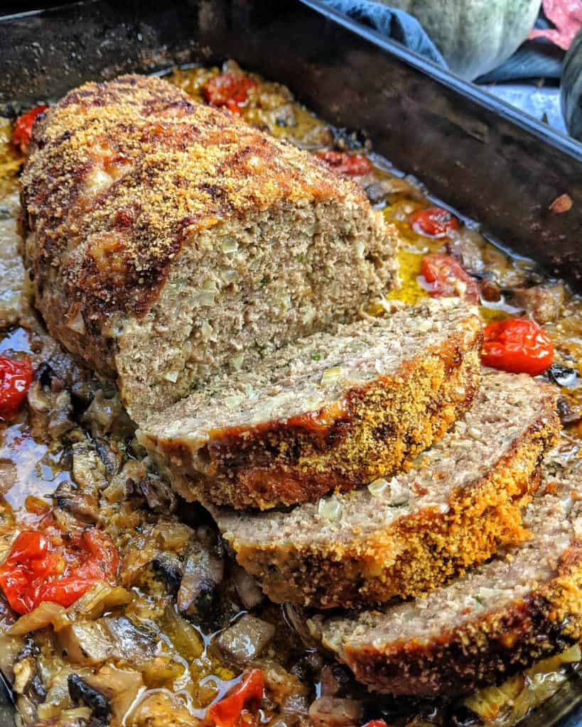 Hackbraten aufgeschnitten in einer Auflaufform mit Soße, Tomaten und Champignons