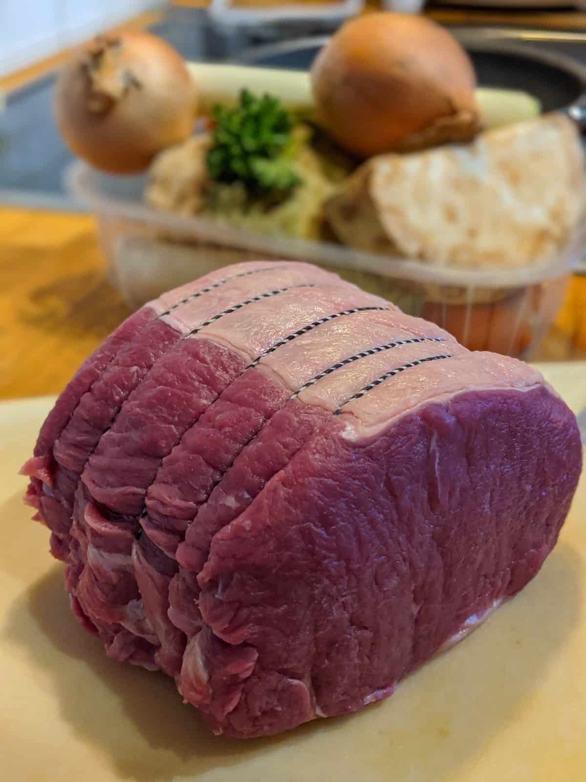 Ein Roastbeef Braten auf einem Schneidebrett vor der Zubereitung.