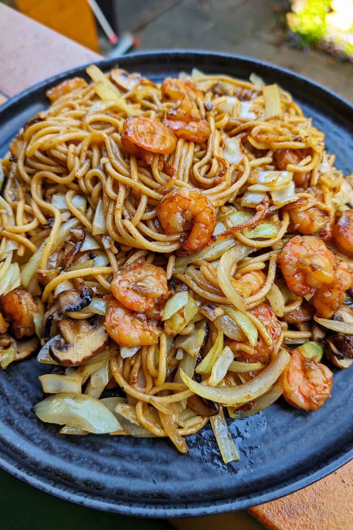 Eine Nahaufnahme von einem dunklen Teller mit Shrimp Chow Mein.