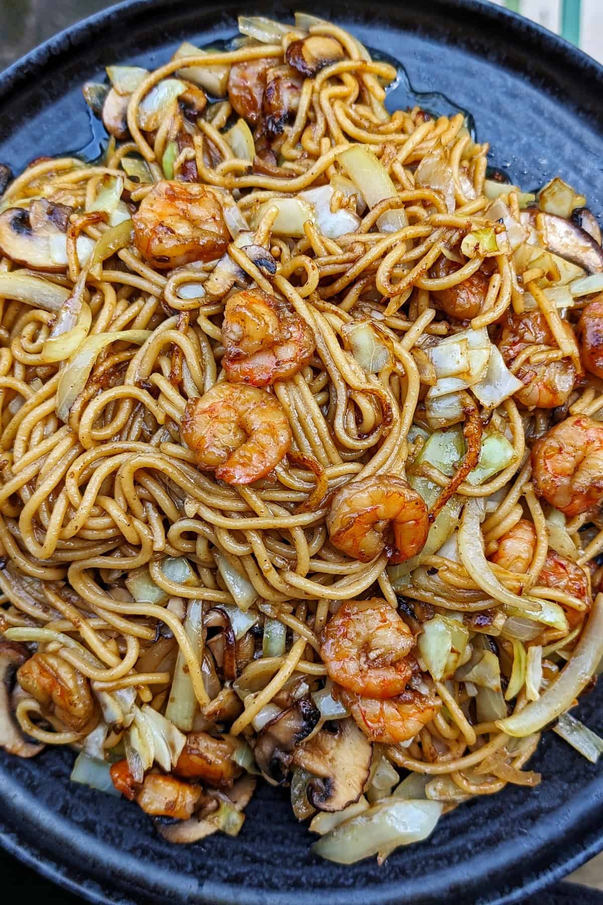 Eine Nahaufnahme von einem dunklen Teller mit Shrimp Chow Mein.