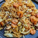 Eine Nahaufnahme von einem dunklen Teller mit Shrimp Chow Mein.