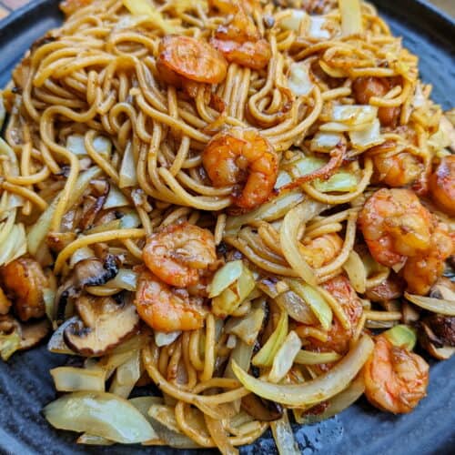 Eine Nahaufnahme von einem dunklen Teller mit Shrimp Chow Mein.