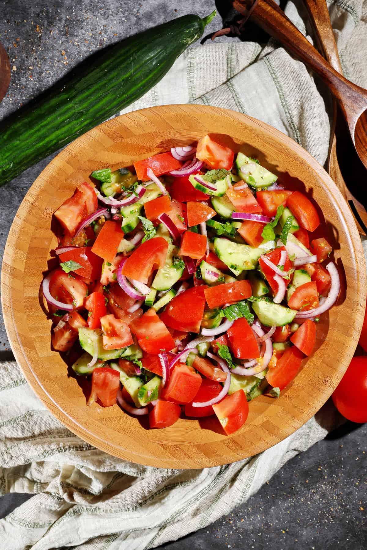 Eine Salatschüssel aus Holz mit dem Tomaten-Gurke Salat.