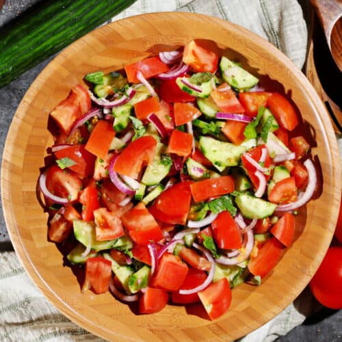 Eine Salatschüssel aus Holz mit dem Tomaten-Gurke Salat.