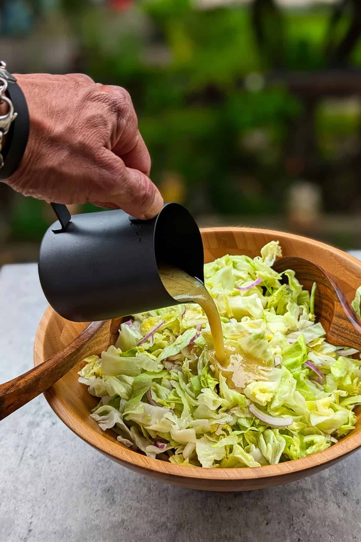 Eine Salatschüssel mit grünem Salat mit Honig-Senf Dressing in die Dressing gegossen wird.