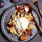 Ein Teller mit einer Portion Pflaumen Crumble und Schlagsahne.