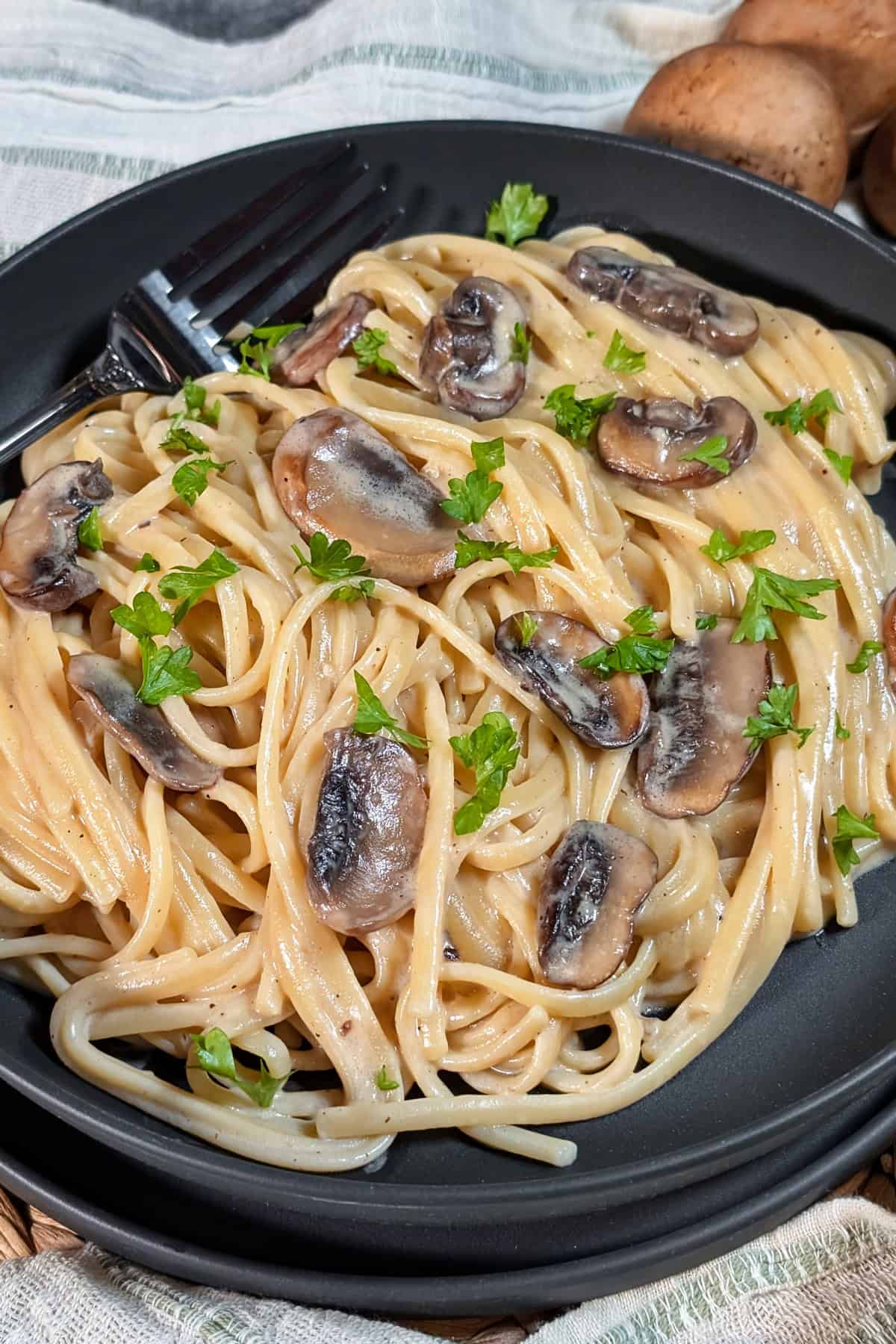 Ein dunkler tiefer Teller mit Rahm Champignons und Spaghetti.