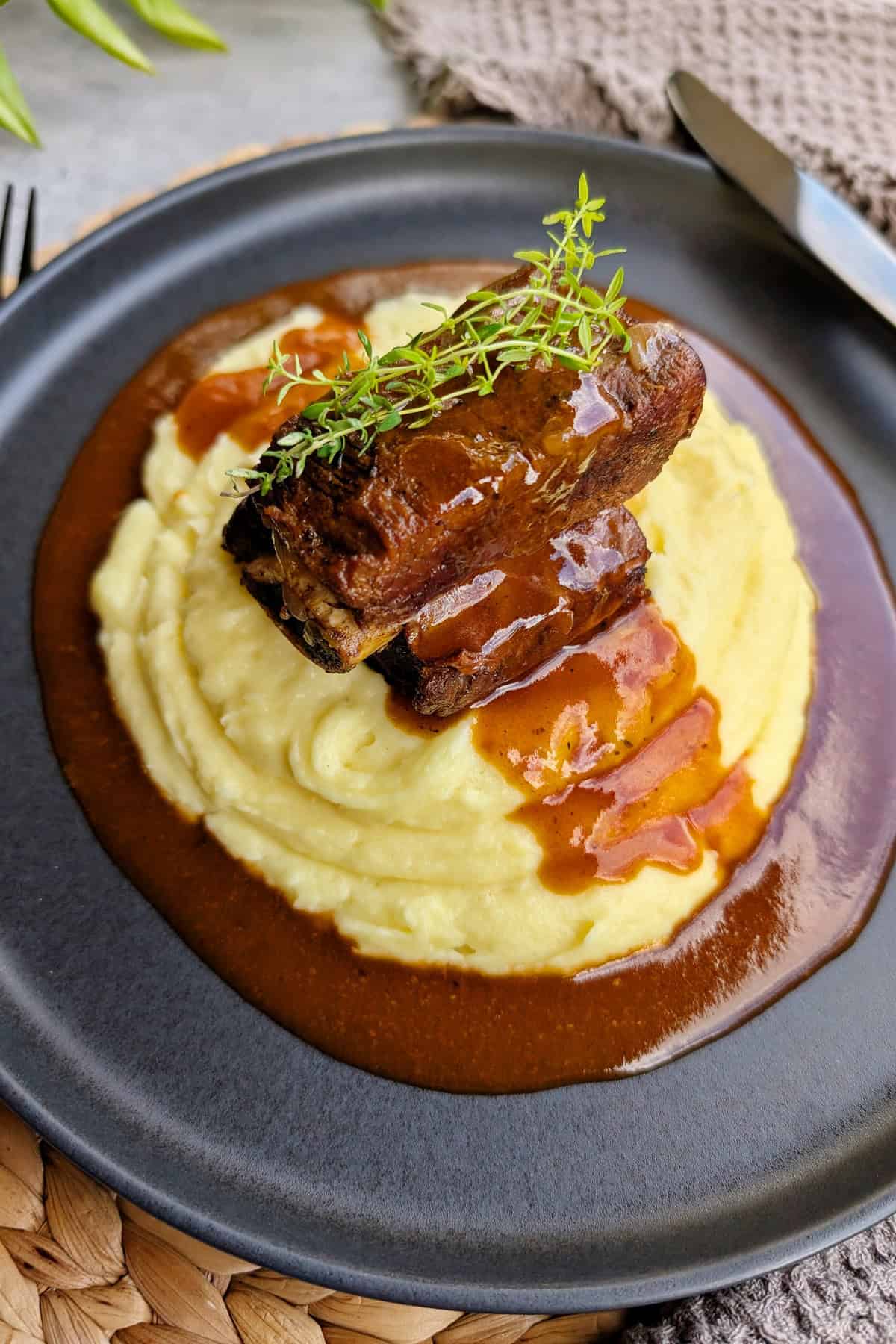 Ein Teller mit Short Ribs, Soße und Kartoffelpüree.