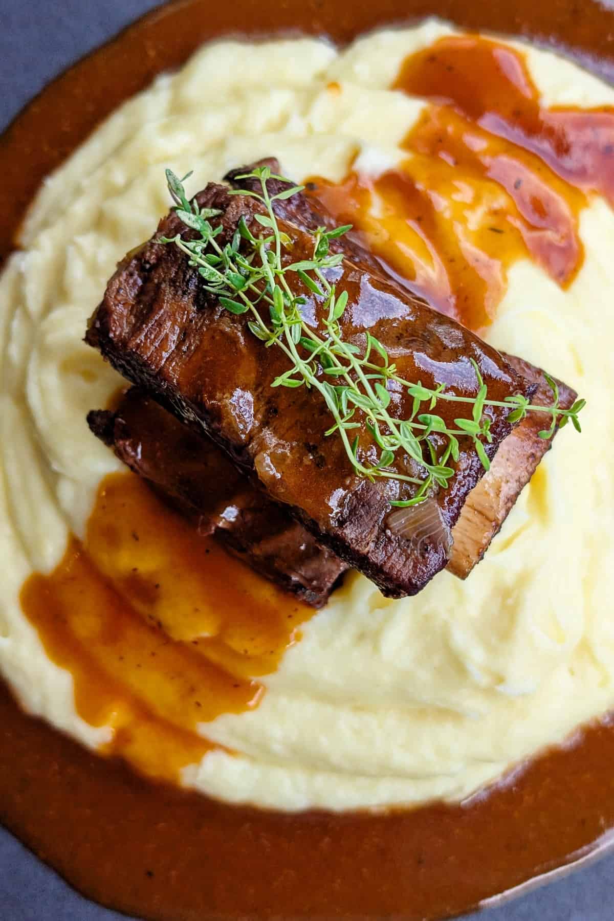 Eine Nahaufnahme eines Tellers mit Short Ribs, Soße und Kartoffelpüree.