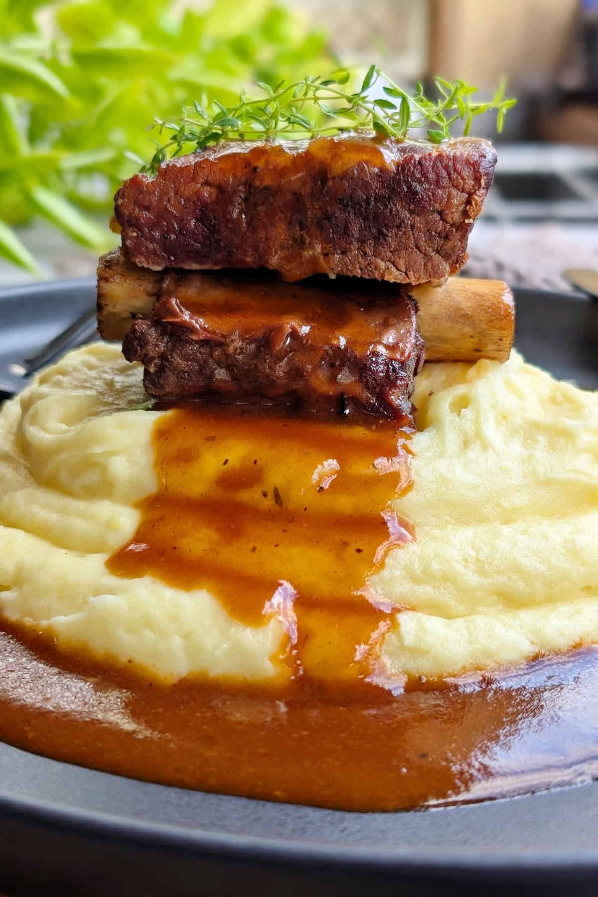 Ein Teller mit Short Ribs, Soße und Kartoffelpüree.