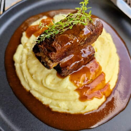 Ein Teller mit Short Ribs, Soße und Kartoffelpüree.